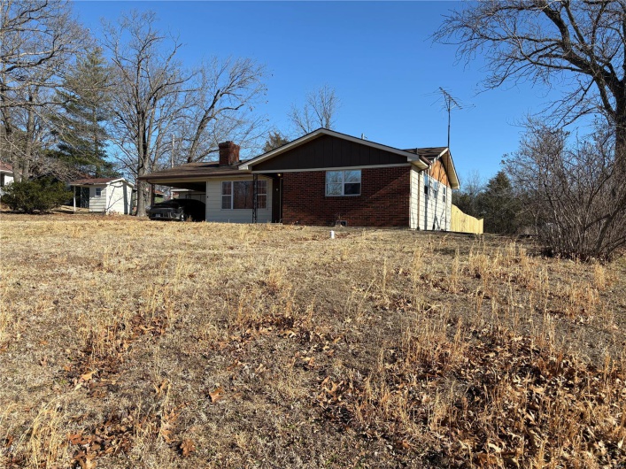 View of front of house featuring an attached carport, brick siding, and a chimney