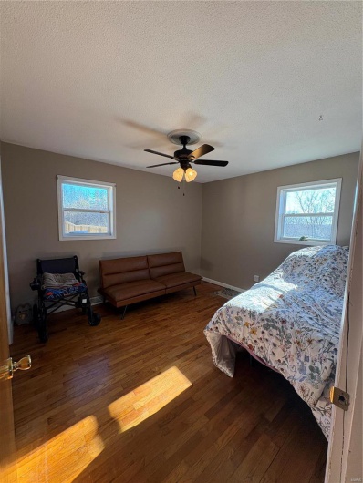Bedroom featuring hardwood / wood-style flooring, ceiling fan, multiple windows, and a textured ceiling