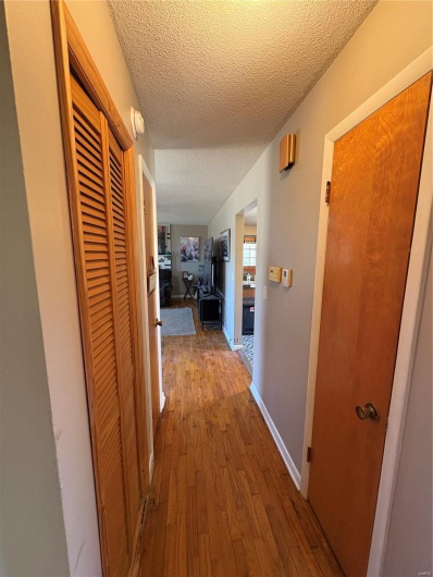 Corridor featuring hardwood / wood-style flooring, baseboards, and a textured ceiling