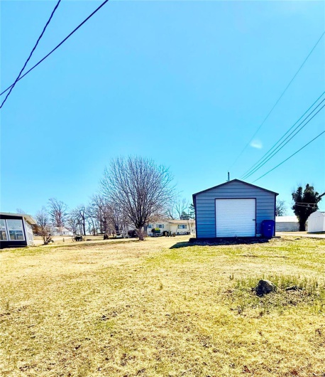 View of yard featuring a garage, an outbuilding, and driveway