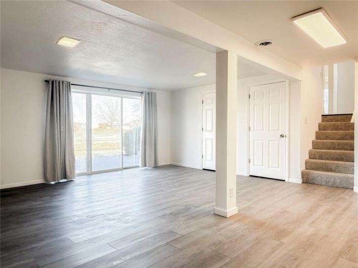 Unfurnished living room featuring baseboards, stairs, visible vents, and wood finished floors