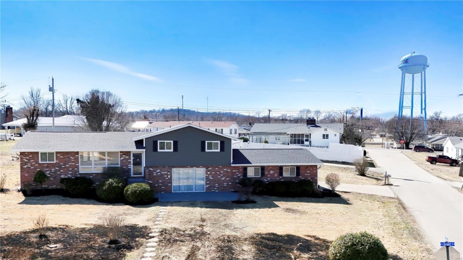Tri-level home featuring a residential view, brick siding, and roof with shingles