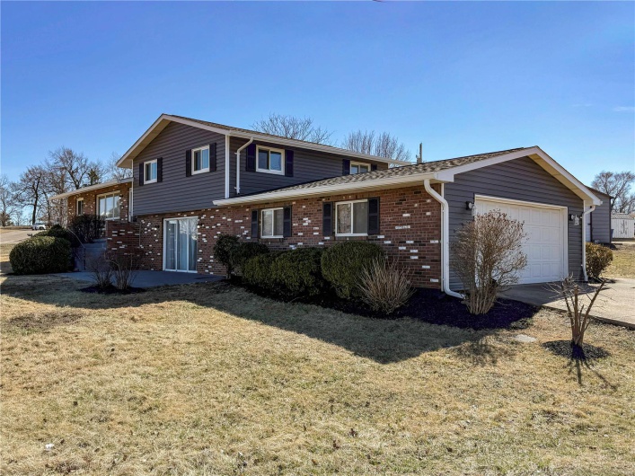 View of front of home featuring concrete driveway, brick siding, a front lawn, and an attached garage