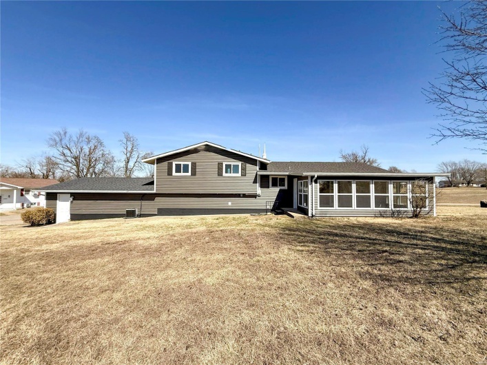 Tri-level home featuring a sunroom and a front lawn