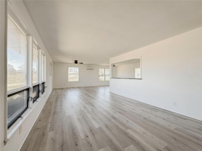 Unfurnished living room with light wood-style flooring, baseboards, and a ceiling fan