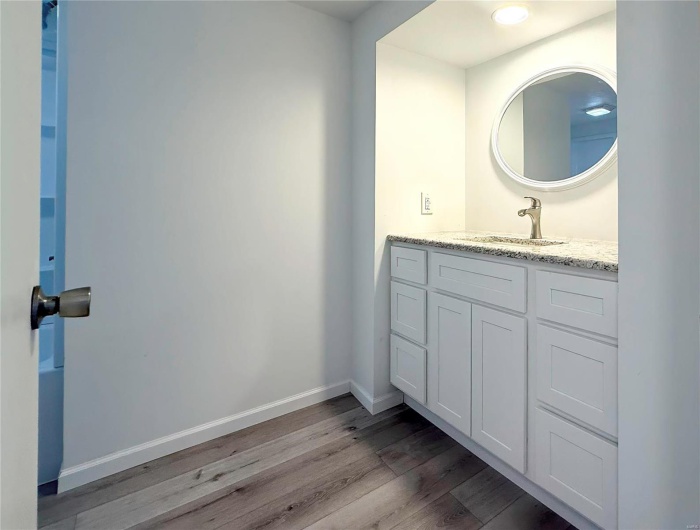 Bathroom featuring vanity, baseboards, and wood finished floors