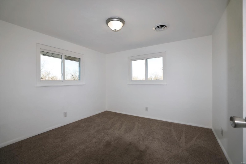 Unfurnished room featuring visible vents, dark carpet, and baseboards