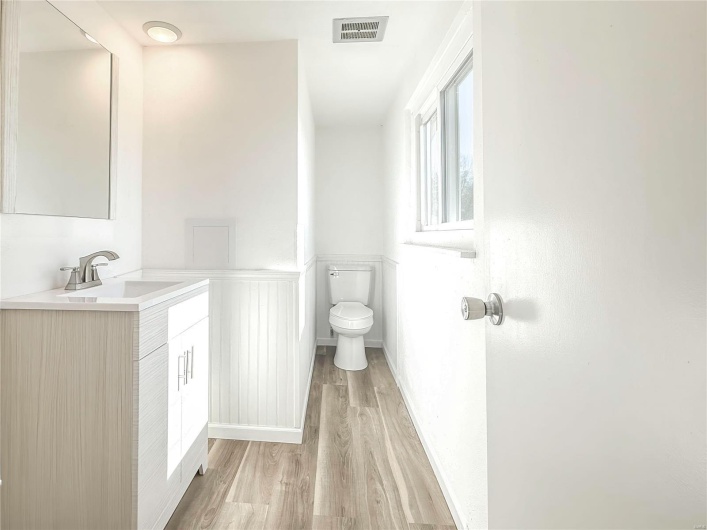 Bathroom with toilet, visible vents, wood finished floors, and vanity