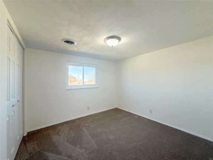 Unfurnished room with baseboards, visible vents, and dark colored carpet