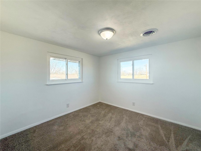 Empty room featuring baseboards, visible vents, and dark carpet