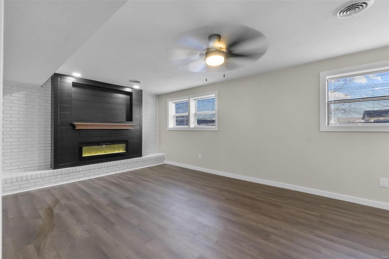 Unfurnished living room featuring a fireplace, visible vents, a ceiling fan, wood finished floors, and baseboards