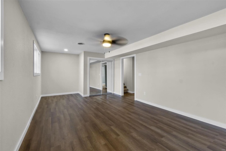 Spare room featuring ceiling fan, recessed lighting, dark wood-style flooring, baseboards, and stairway