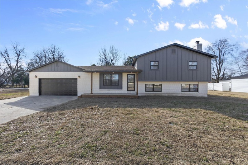 Split level home featuring a garage, concrete driveway, brick siding, and board and batten siding