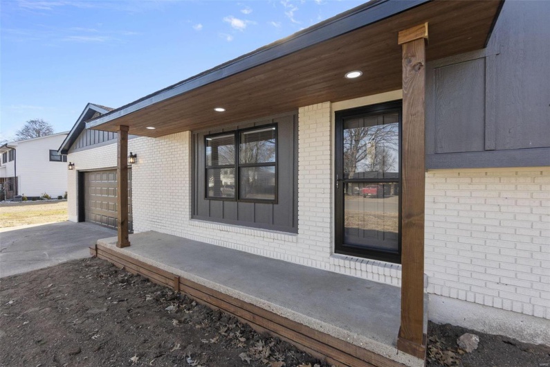 View of side of property with a garage, driveway, and brick siding