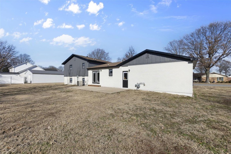 Rear view of property with a patio area, a lawn, and brick siding