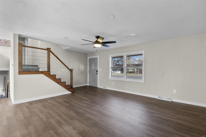 Unfurnished living room with baseboards, visible vents, ceiling fan, wood finished floors, and stairs