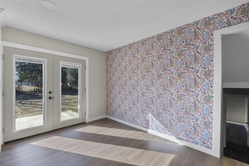 Spare room featuring baseboards, french doors, wood finished floors, and wallpapered walls
