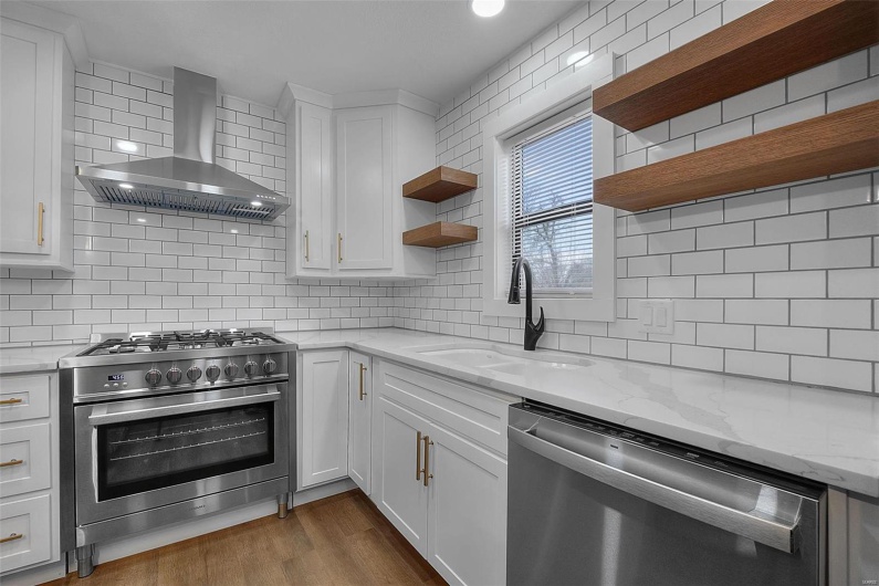 Kitchen with a sink, appliances with stainless steel finishes, wall chimney range hood, decorative backsplash, and open shelves