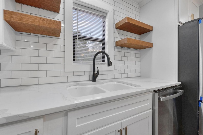 Kitchen with open shelves, backsplash, appliances with stainless steel finishes, white cabinetry, and a sink