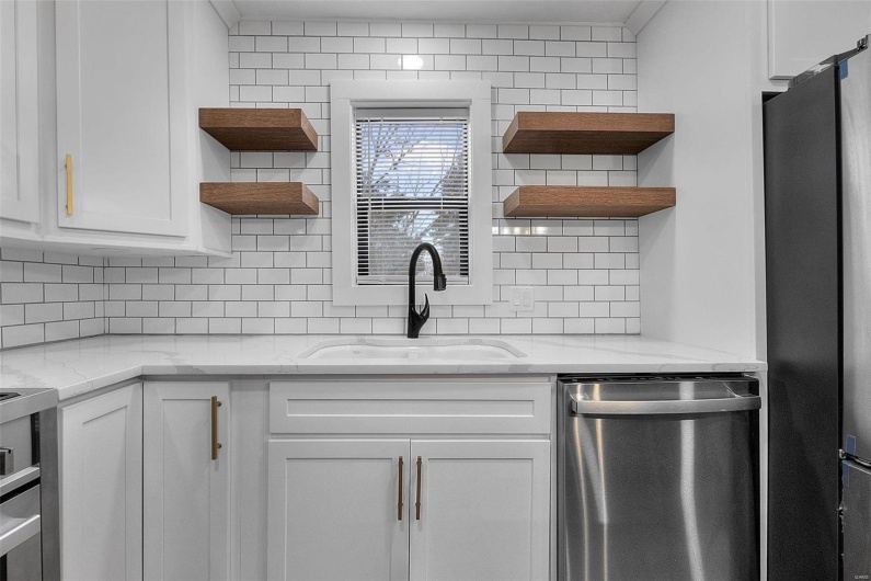 Kitchen featuring stainless steel appliances, white cabinets, a sink, and open shelves