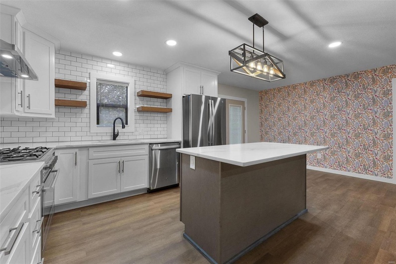 Kitchen featuring wallpapered walls, appliances with stainless steel finishes, dark wood-type flooring, open shelves, and a sink