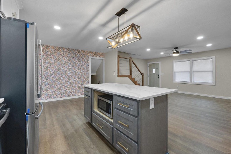 Kitchen with gray cabinetry, stainless steel appliances, baseboards, dark wood-style floors, and wallpapered walls