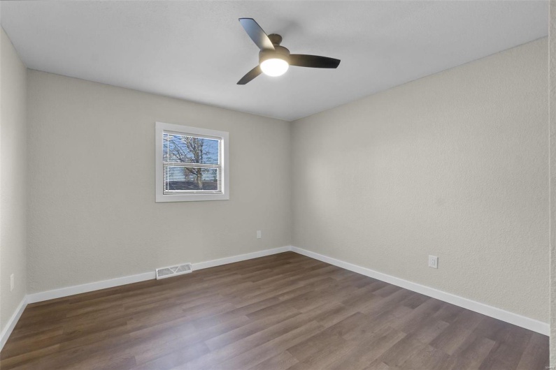 Spare room featuring baseboards, visible vents, dark wood finished floors, and a ceiling fan