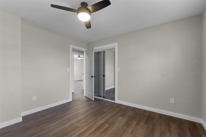 Empty room with dark wood-style floors, ceiling fan, and baseboards