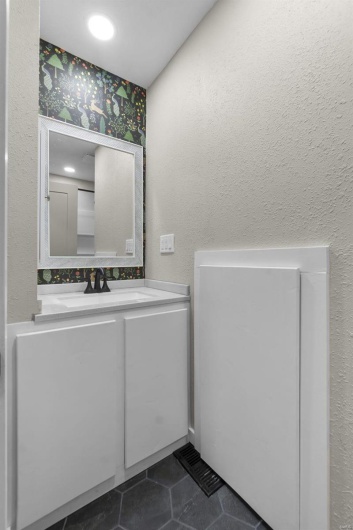 Bathroom featuring a textured wall, tile patterned flooring, and vanity