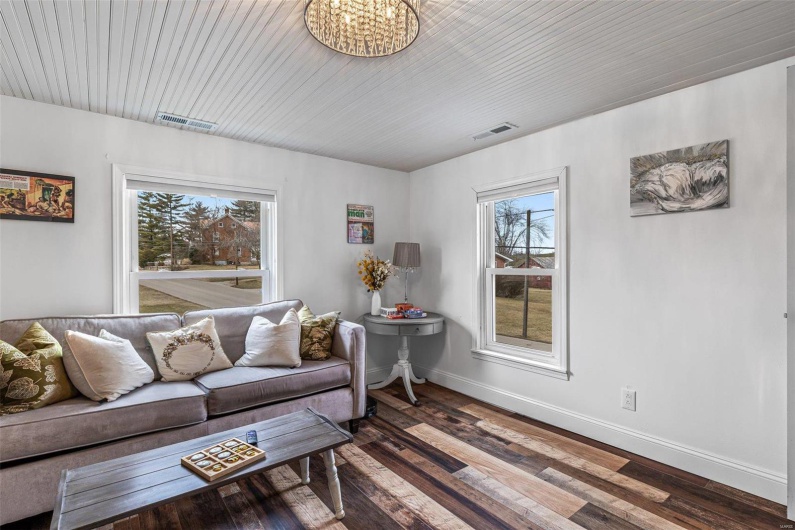 Living room featuring a notable chandelier, wood finished floors, visible vents, and baseboards