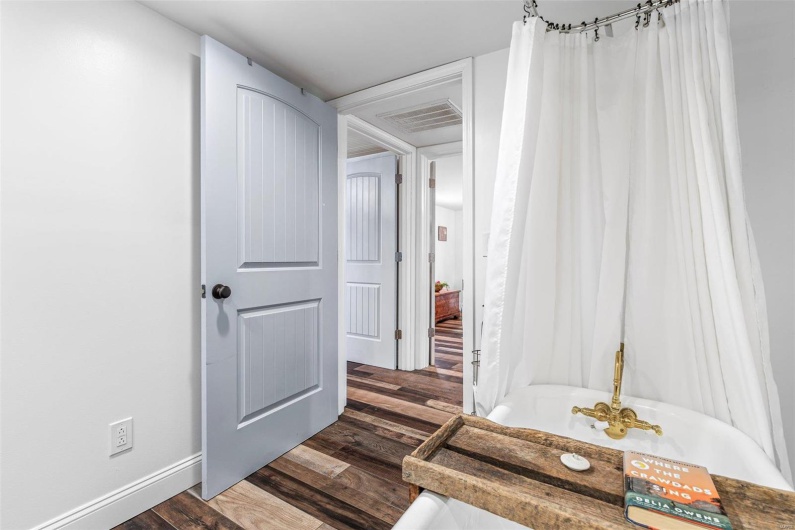 Hallway featuring dark wood finished floors, visible vents, and baseboards