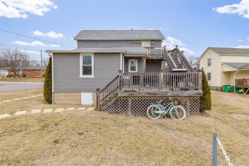Rear view of house with roof with shingles, a lawn, a wooden deck, and stairs