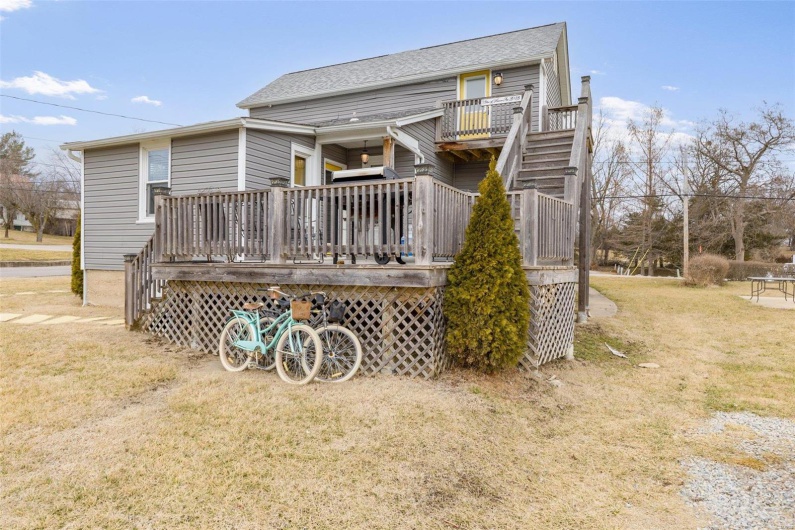 Rear view of property featuring a yard, a shingled roof, stairs, and a wooden deck