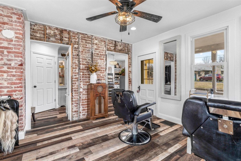 Home office featuring brick wall, ceiling fan, baseboards, and wood finished floors