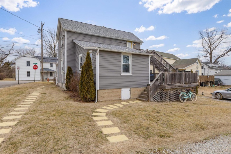 Back of house featuring roof with shingles, stairs, a wooden deck, and a yard