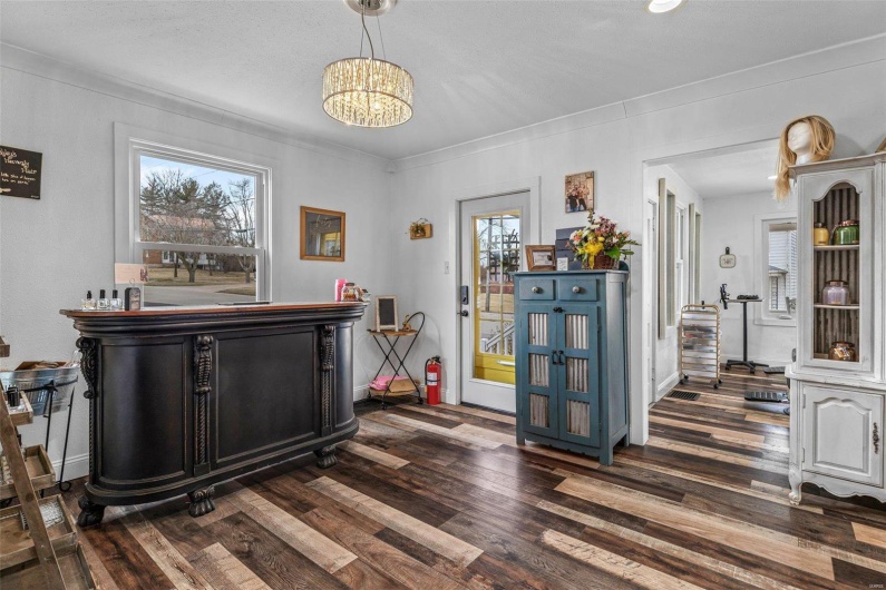 Bar with a notable chandelier, plenty of natural light, and wood finished floors