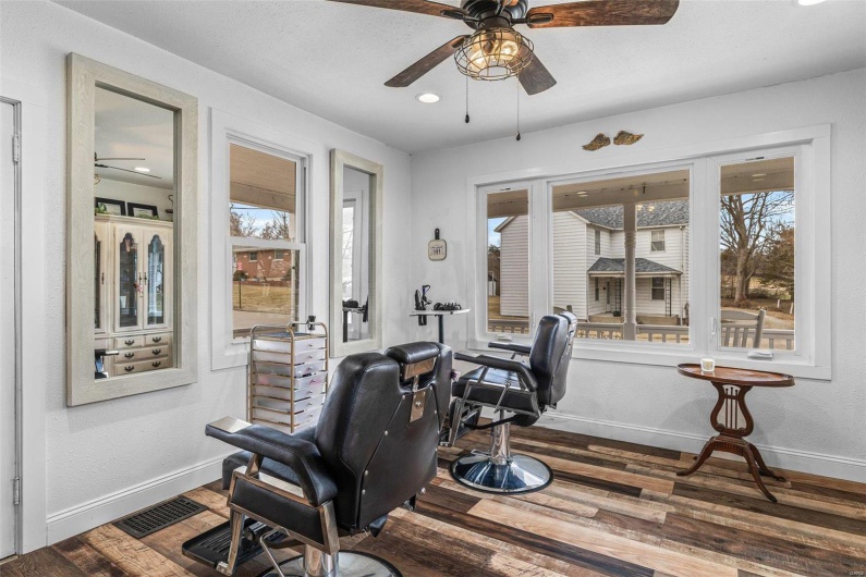 Home office with ceiling fan, wood finished floors, visible vents, and baseboards