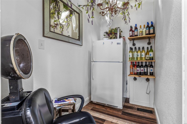 Bar featuring a textured wall, wood finished floors, freestanding refrigerator, and baseboards