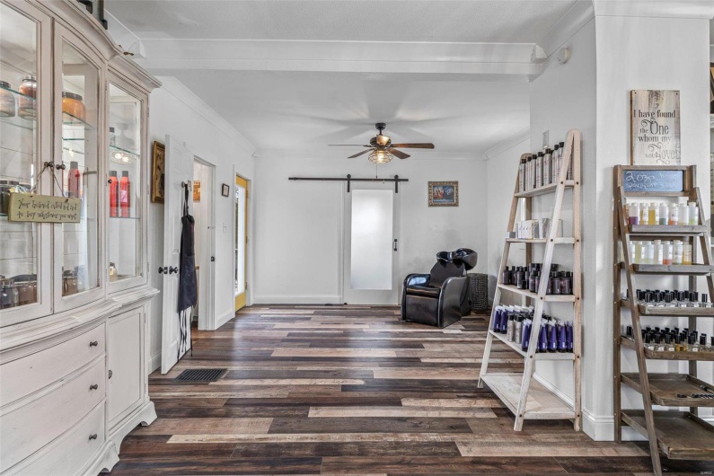 Living area with a barn door, baseboards, ceiling fan, ornamental molding, and dark wood-style flooring