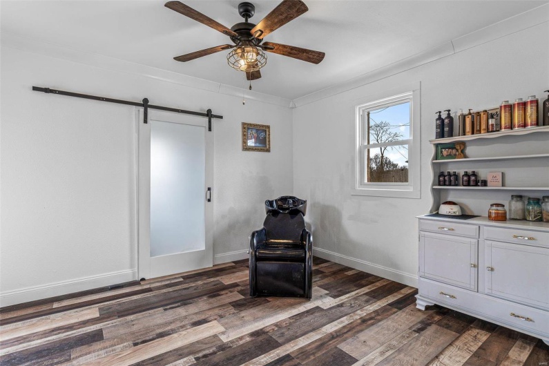 Sitting room featuring dark wood-style flooring, crown molding, a barn door, a ceiling fan, and baseboards
