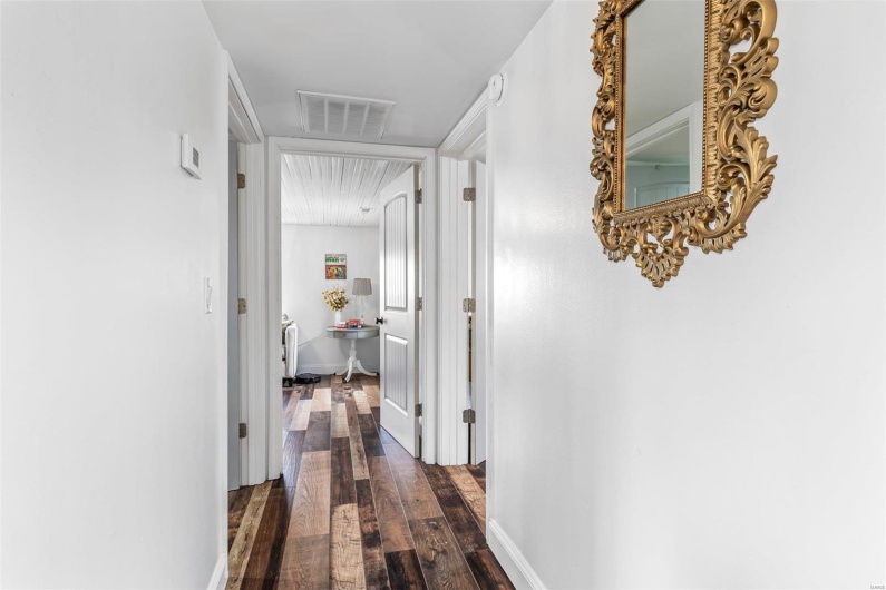 Corridor with baseboards, visible vents, and dark wood finished floors