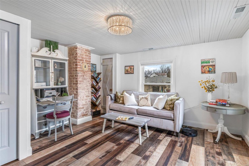 Living area featuring a notable chandelier, wood-type flooring, visible vents, and baseboards