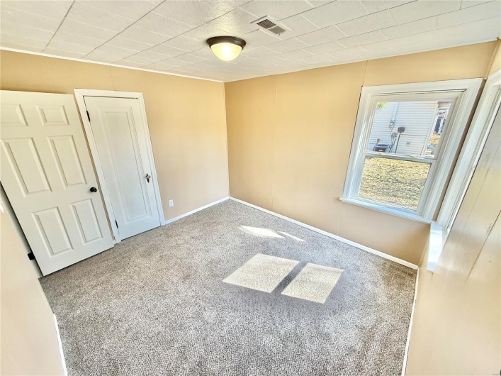 Unfurnished bedroom with a closet, carpet, visible vents, and baseboards