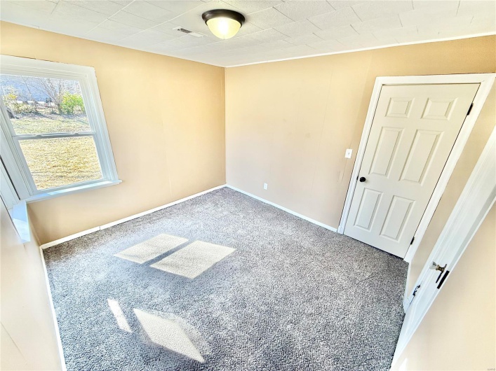 Empty room with carpet, visible vents, and baseboards