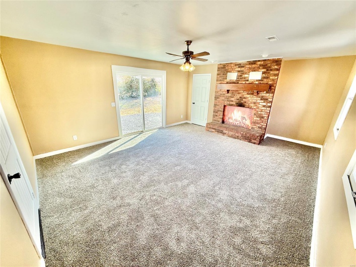 Unfurnished living room featuring carpet, a fireplace, visible vents, a ceiling fan, and baseboards