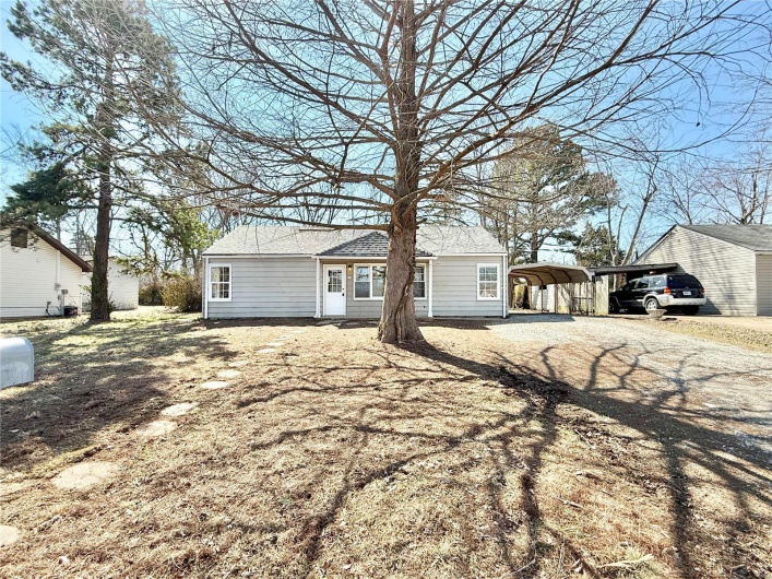 Ranch-style house with driveway, a shingled roof, and a detached carport