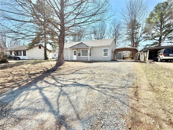 View of front facade with a detached carport and gravel driveway
