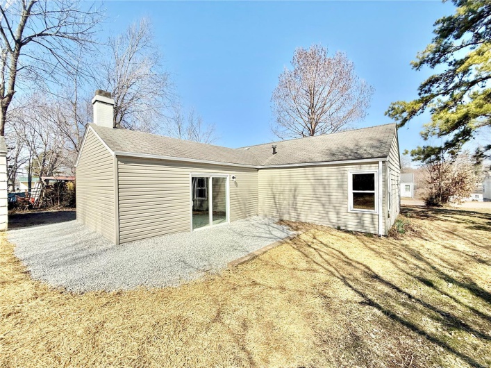 Rear view of property with roof with shingles, a chimney, and a patio area