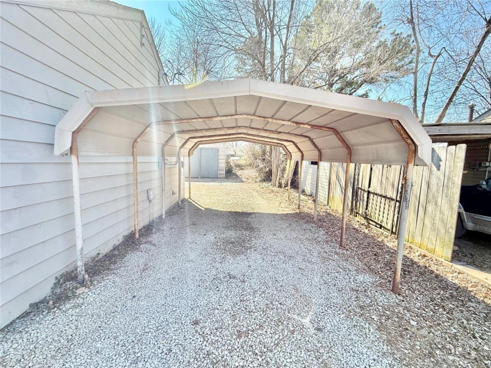View of parking with driveway and a carport