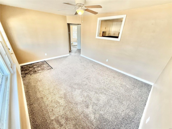 Carpeted empty room with ceiling fan and baseboards